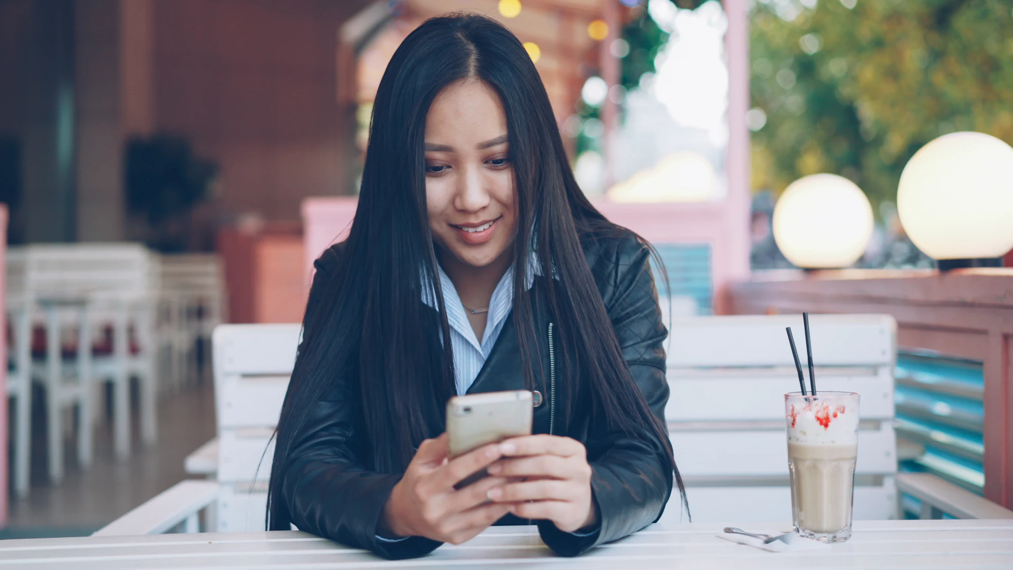 Guest smiling at her phone at an outdoor cafe