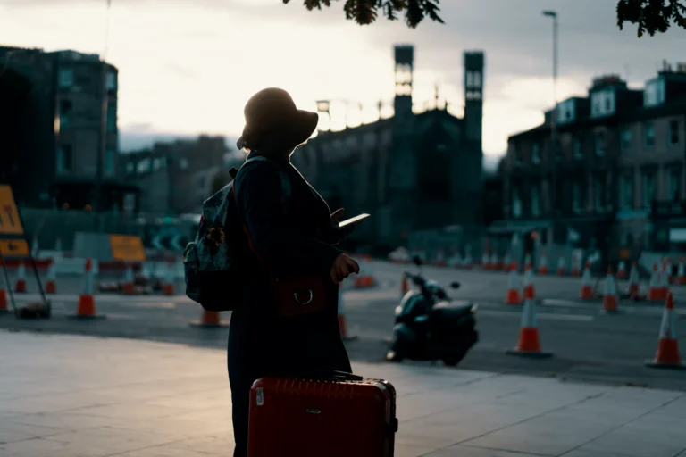 Traveller with luggage checking her phone on a city street